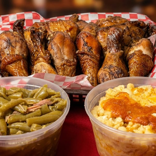 A basket of roasted chicken pieces, with sides of green beans and mac and cheese.